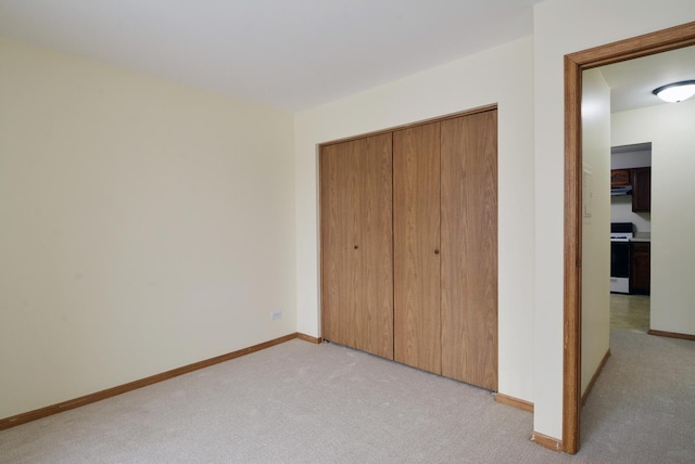 unfurnished bedroom with light colored carpet and a closet