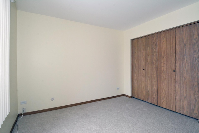 unfurnished bedroom with light colored carpet and a closet