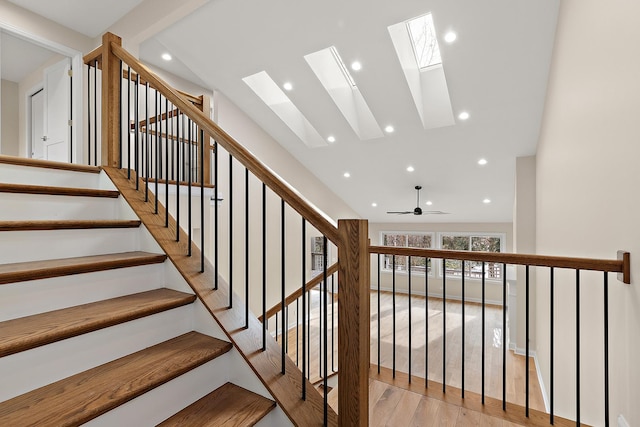 stairway featuring hardwood / wood-style flooring, a skylight, and high vaulted ceiling