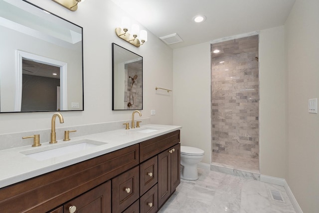 bathroom with a tile shower, vanity, and toilet