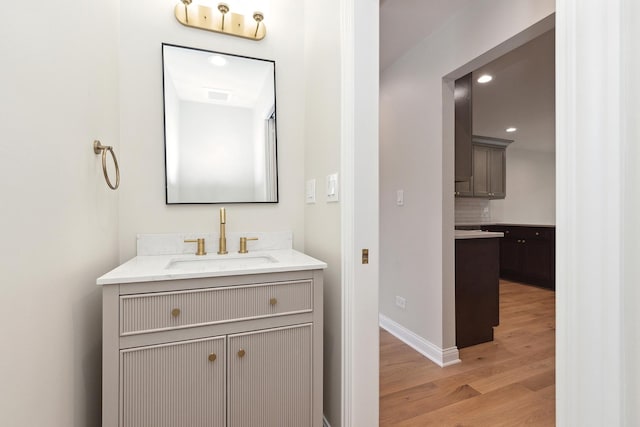 bathroom with hardwood / wood-style flooring, vanity, and backsplash