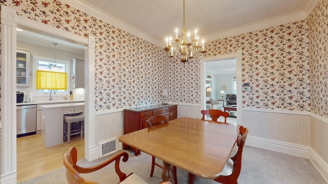 dining room with a healthy amount of sunlight, ornamental molding, sink, and light wood-type flooring