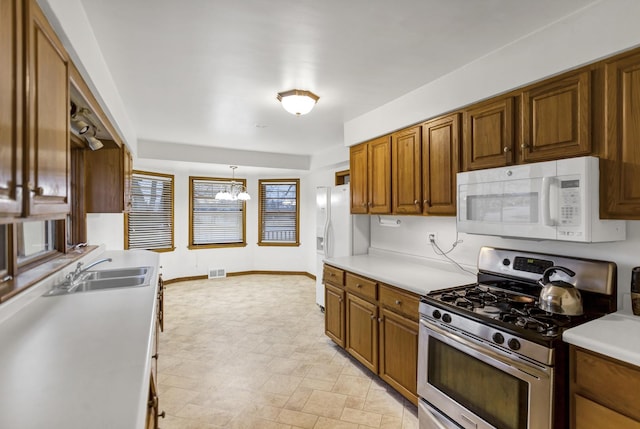 kitchen with an inviting chandelier, sink, white appliances, and decorative light fixtures