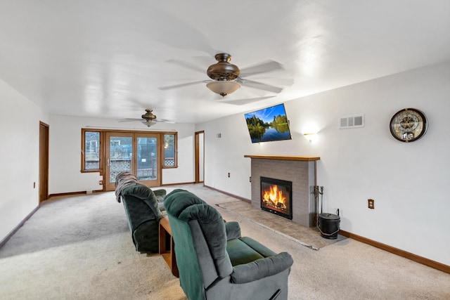 living room featuring a brick fireplace, light colored carpet, and ceiling fan