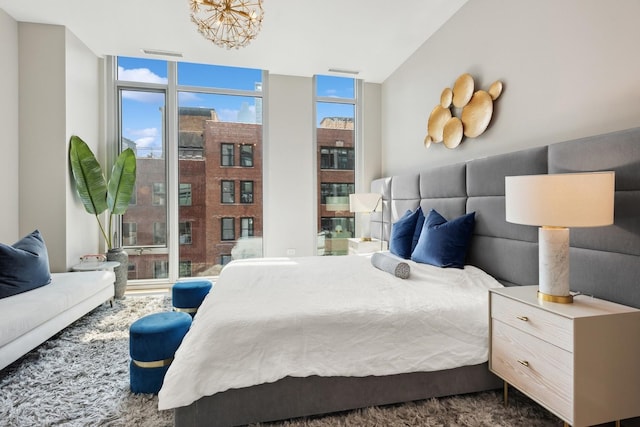 carpeted bedroom with a chandelier and a wall of windows