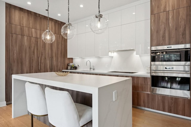 kitchen featuring pendant lighting, white cabinets, stainless steel double oven, sink, and cooktop