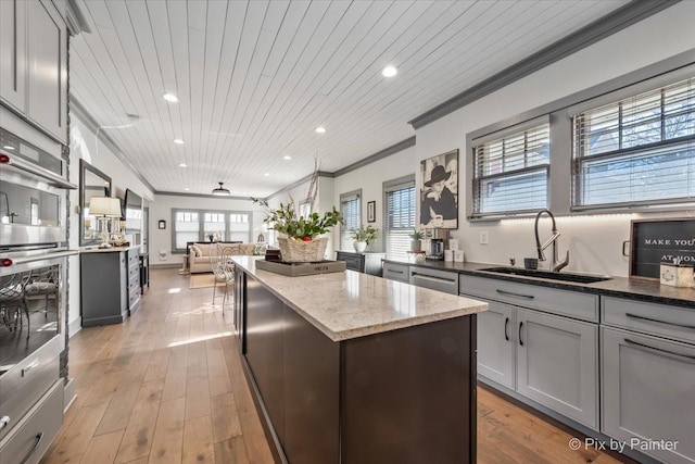 kitchen with sink, a center island, wooden ceiling, gray cabinets, and light stone countertops