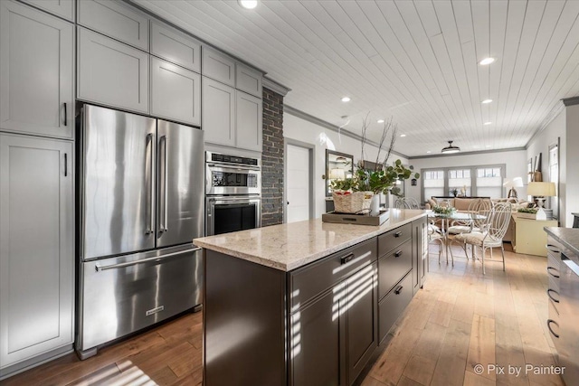 kitchen featuring light stone counters, crown molding, a center island, and appliances with stainless steel finishes