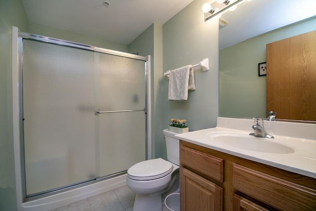 bathroom featuring vanity, toilet, tile patterned floors, and a shower with shower door