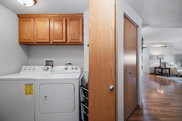 laundry room with dark wood-type flooring, washing machine and dryer, and cabinets