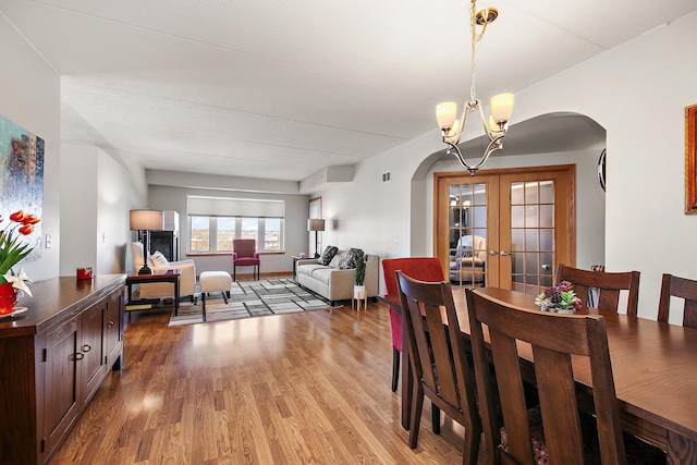 dining space featuring french doors, a chandelier, and light hardwood / wood-style floors