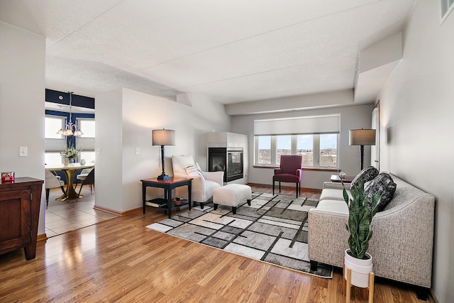 living room featuring hardwood / wood-style flooring, a multi sided fireplace, and an inviting chandelier