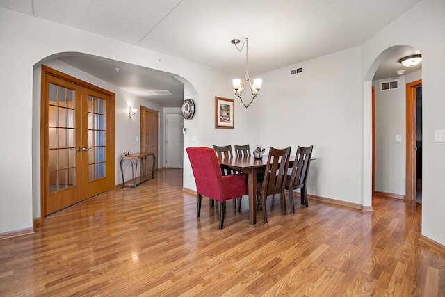 dining room with light hardwood / wood-style flooring, a chandelier, and french doors