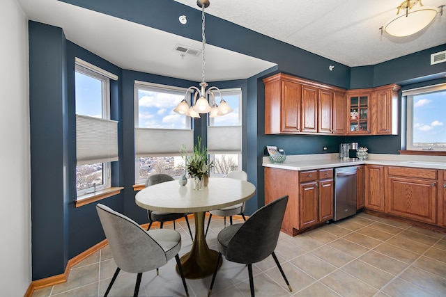 kitchen featuring pendant lighting, dishwasher, light tile patterned floors, and a notable chandelier