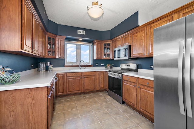 kitchen featuring light tile patterned flooring, stainless steel appliances, sink, and a textured ceiling