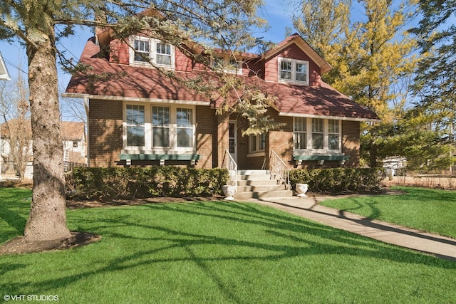 view of front of home featuring a front yard, brick siding, and roof with shingles