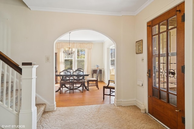 entryway with crown molding, stairs, arched walkways, and a notable chandelier