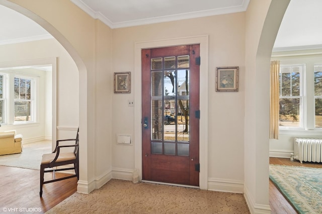 entryway featuring ornamental molding, arched walkways, plenty of natural light, and radiator heating unit