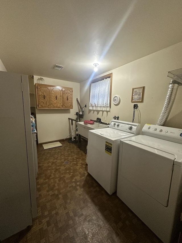 clothes washing area featuring sink, cabinets, and washing machine and clothes dryer