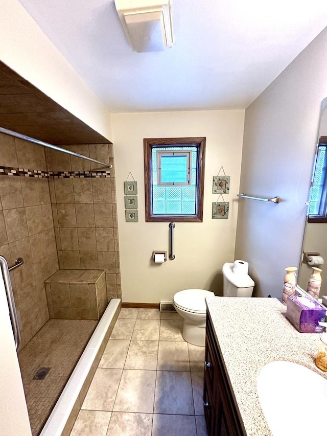 bathroom with vanity, a tile shower, tile patterned floors, and toilet