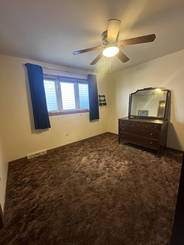 unfurnished bedroom with ceiling fan and dark carpet