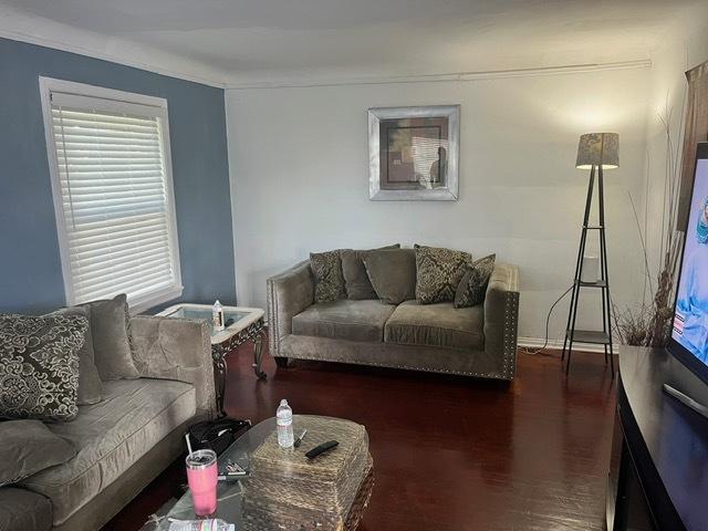 living room with dark hardwood / wood-style flooring and ornamental molding