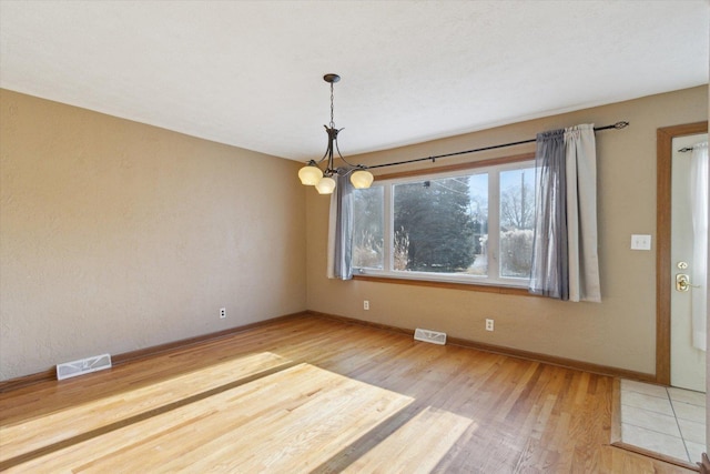 unfurnished dining area with a notable chandelier and hardwood / wood-style floors