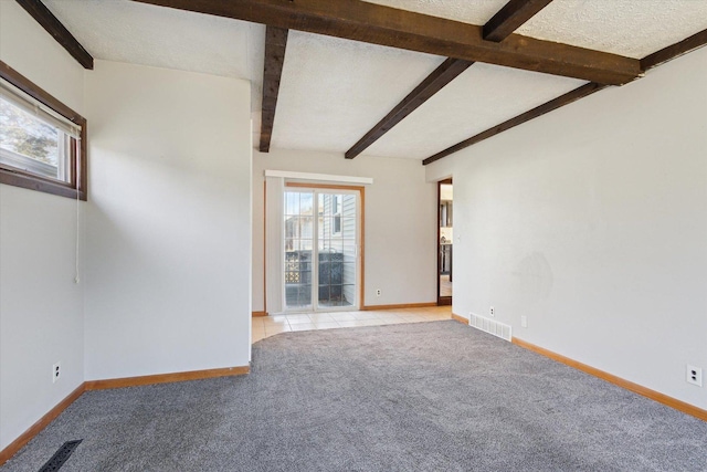 empty room with beamed ceiling, a textured ceiling, and light carpet