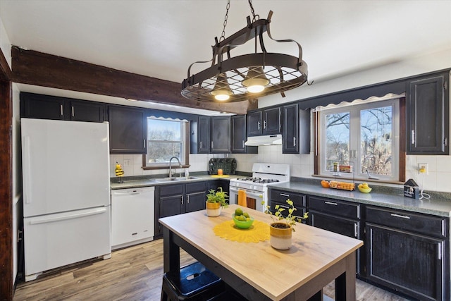 kitchen with sink, white appliances, beam ceiling, and plenty of natural light