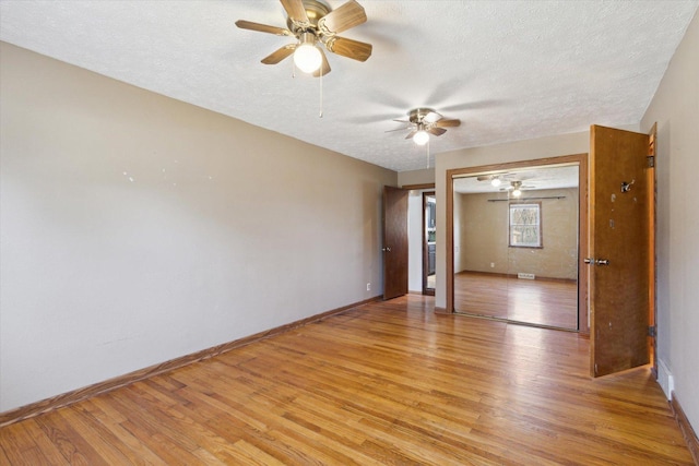 unfurnished room with a textured ceiling and light wood-type flooring