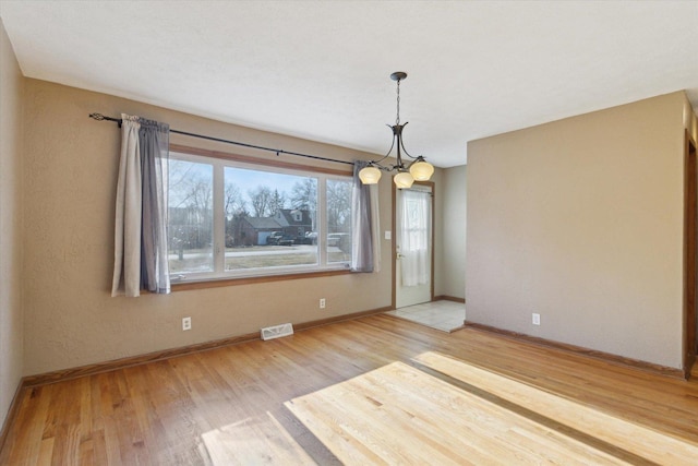 unfurnished dining area with hardwood / wood-style flooring and a chandelier