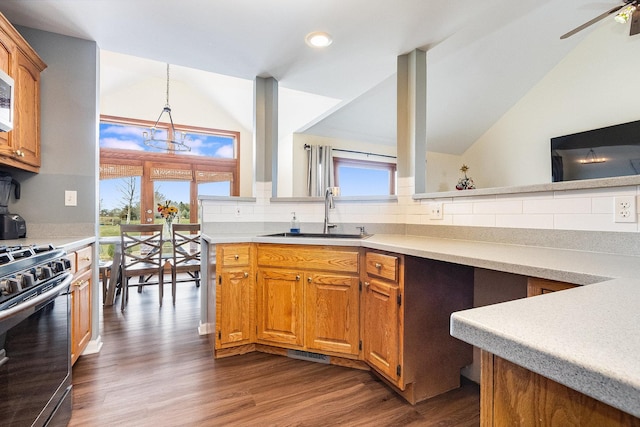 kitchen with sink, decorative light fixtures, gas stove, dark hardwood / wood-style flooring, and lofted ceiling