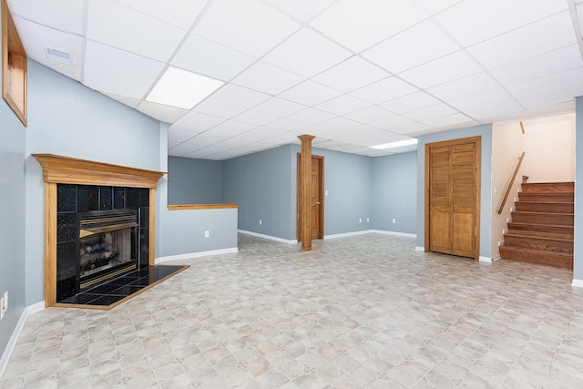 unfurnished living room featuring a tile fireplace and a drop ceiling