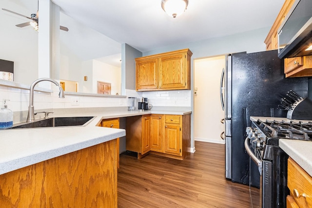 kitchen featuring stainless steel gas range, dark wood-type flooring, decorative backsplash, sink, and range hood