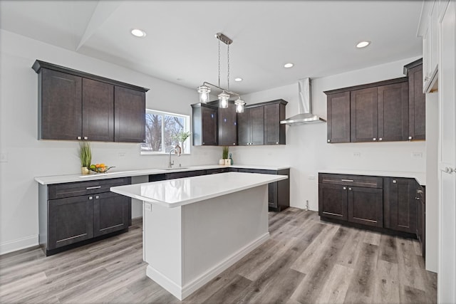 kitchen featuring a kitchen island, decorative light fixtures, sink, dark brown cabinetry, and wall chimney exhaust hood