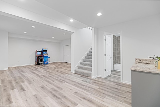 basement with light hardwood / wood-style floors and sink