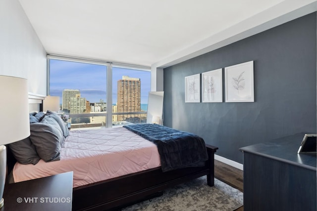 bedroom with expansive windows and hardwood / wood-style floors