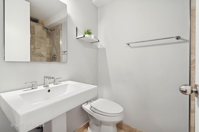 bathroom with toilet, sink, and a tile shower