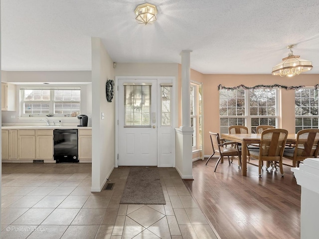 foyer with decorative columns, light tile patterned floors, a textured ceiling, and sink