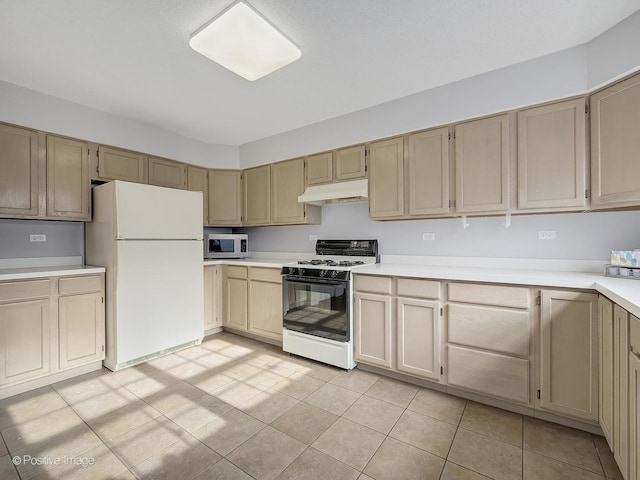 kitchen featuring gas range, light tile patterned floors, and white fridge