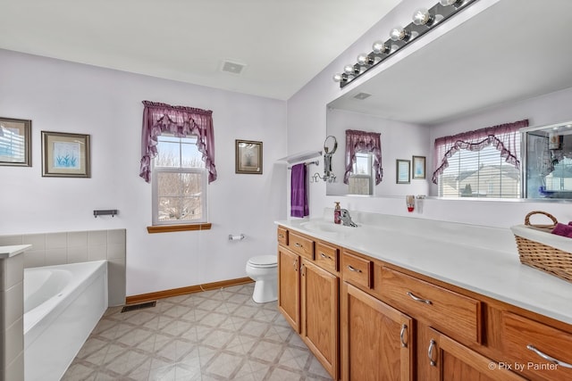 bathroom featuring vanity, plenty of natural light, a washtub, and toilet