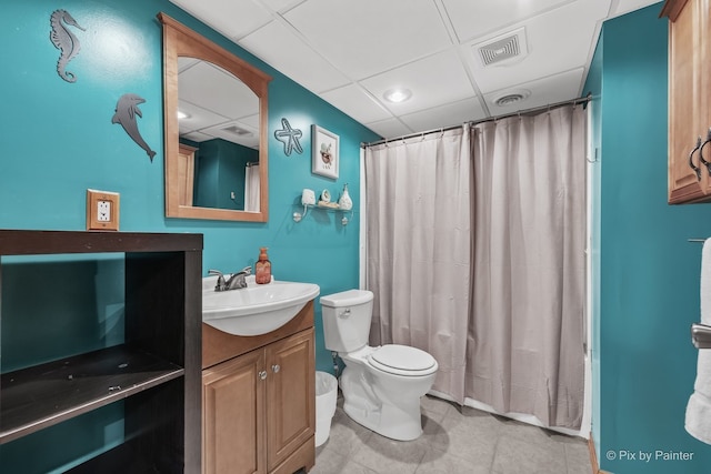 full bathroom featuring toilet, a paneled ceiling, vanity, and shower / bathtub combination with curtain