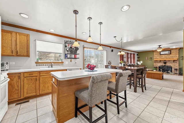 kitchen with sink, a breakfast bar area, a center island, ornamental molding, and pendant lighting