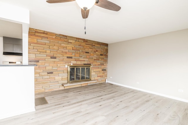 unfurnished living room featuring ceiling fan, a large fireplace, and light wood-type flooring