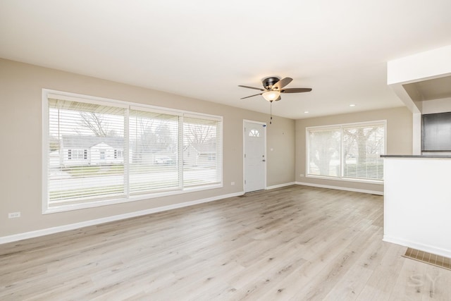 unfurnished living room featuring a wealth of natural light, ceiling fan, and light wood-type flooring