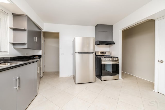 kitchen featuring wall chimney range hood, sink, gray cabinetry, stainless steel appliances, and light tile patterned flooring