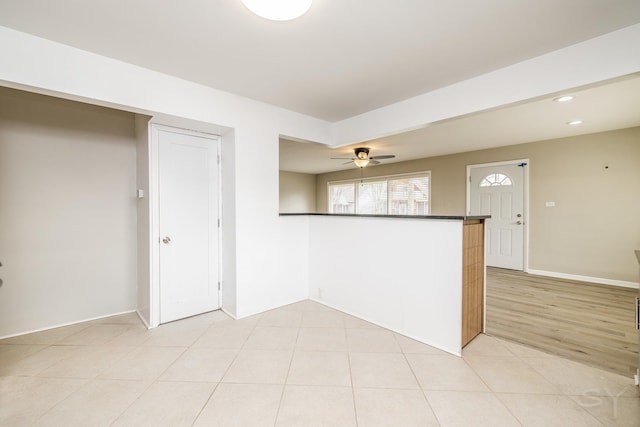 kitchen with light tile patterned flooring, ceiling fan, and kitchen peninsula