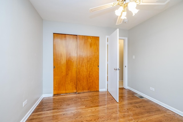 unfurnished bedroom featuring ceiling fan, light hardwood / wood-style floors, and a closet