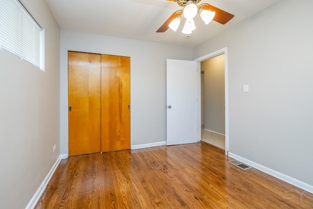 unfurnished bedroom featuring ceiling fan, wood-type flooring, and a closet