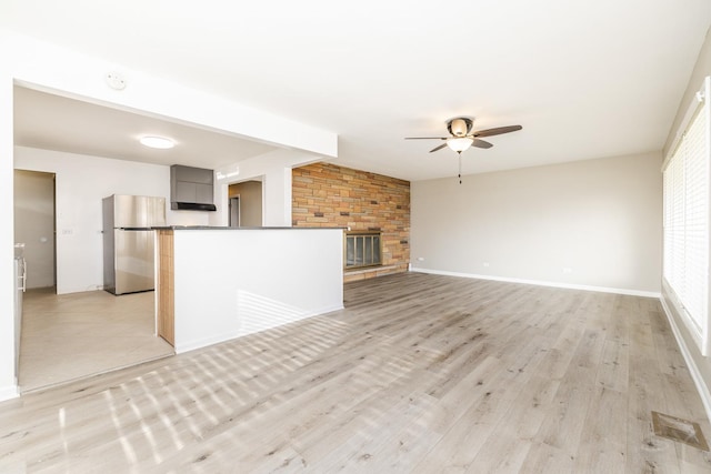 unfurnished living room with light hardwood / wood-style flooring, a fireplace, lofted ceiling, and ceiling fan